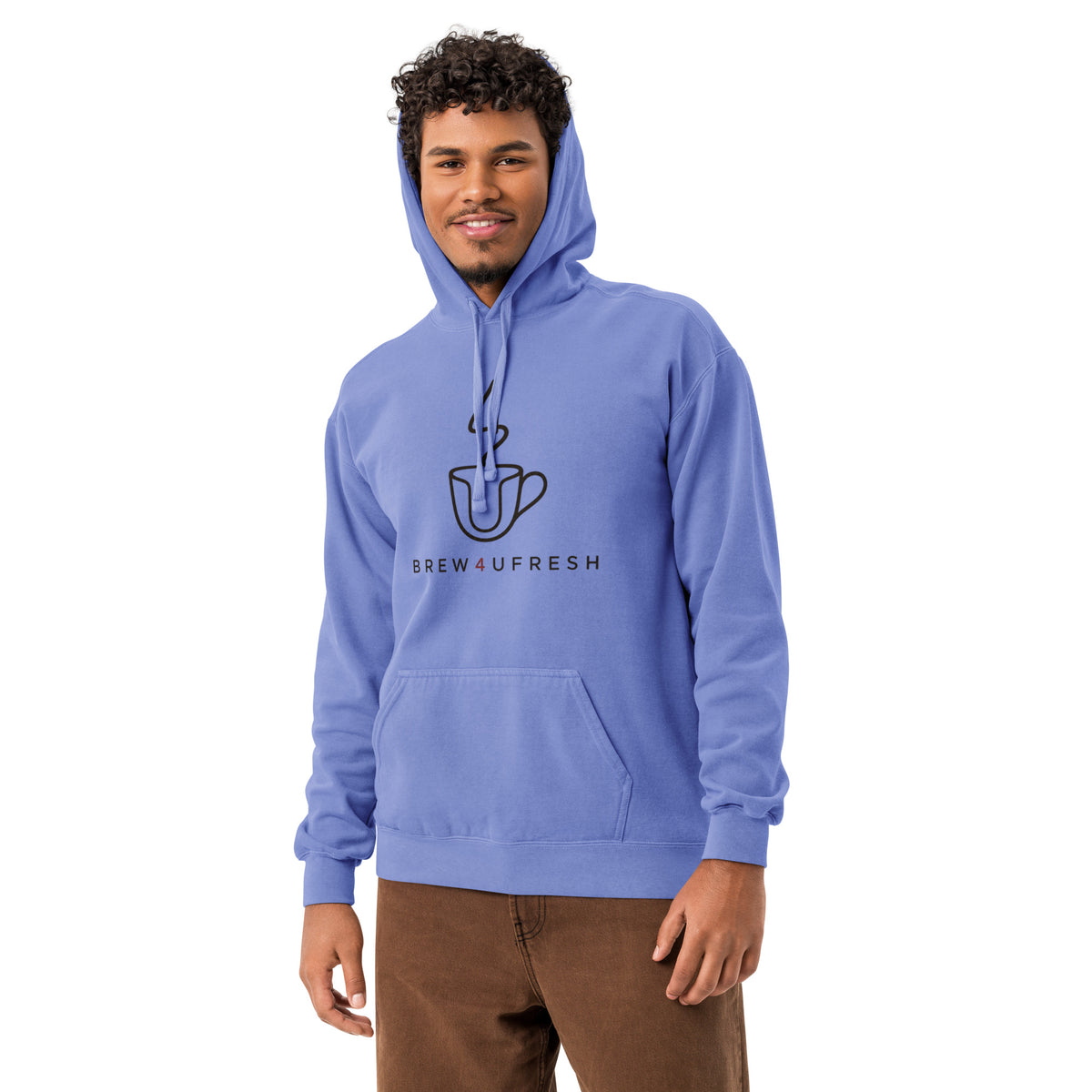 Garment-dyed hoodie in light blue with a front pouch pocket and logo, worn casually by a model with curly hair.